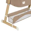 Close-up view of the lower section of a baby crib or bassinet, showing wooden legs and a beige fabric storage basket. Náhľad obrázku produktu
