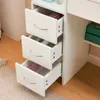 A close-up view of the drawers of a white vanity table. Voir les images du produit