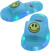 Paar hellblaue Rutschesandalen mit gelbem Smiley-Gesicht auf dem Riemen und bunten LED-Leuchten in der Sohle