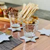 Two clear glasses sit on star-shaped coasters on a wooden table, with snacks in the background. Produktbild-Vorschau
