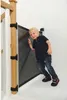 A young child is leaning against a black mesh baby gate installed on a wooden banister. Náhľad obrázku produktu