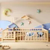 A child's bed with a house-shaped frame, decorated with moon and star pillows and wall decorations. Voir les images du produit