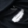 A close-up of dark blue fabric with a white feather on it. Voir les images du produit