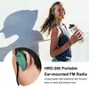 A woman is holding a water bottle and wearing an ear-mounted FM radio while exercising outdoors. A close-up inset shows the earphone in detail. Voir les images du produit