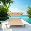 A double lounge chair with a canopy sits on a patio next to a swimming pool with a view of the ocean. Voir les images du produit