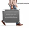 A person is carrying a folded gray lounger. Produktbild-Vorschau