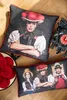 Two pillows with traditional German attire printed on them are displayed on a wooden floor, next to a cuckoo clock. Produktbild-Vorschau
