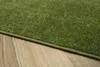 A close-up view of a green rug with a textured surface, placed on a wooden floor. Voir les images du produit