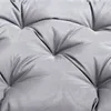 A close-up view of a gray tufted cushion. Voir les images du produit