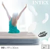 A woman is stretching on an inflatable mattress, with feathers floating around. Podgląd zdjęcia produktu