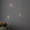 Three starburst-shaped LED lights are displayed against a plain gray background. A bowl of decorative items is visible in the lower left corner. Produktbild-Vorschau