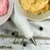 A close-up overhead view of baking supplies, including piping bags, frosting, and piping tips, arranged on a distressed wooden surface. Anteprima dell’immagine prodotto