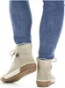 A person wearing blue jeans and beige boots. Voir les images du produit
