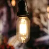 A close-up shot of a vintage-style LED light bulb hanging from a black socket against a blurred, colorful background. Podgląd zdjęcia produktu