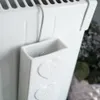A close-up shot of a white ceramic radiator humidifier with heart decorations, hanging on a white radiator. Voir les images du produit