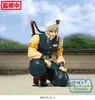 A figure of Tengen Uzui from Demon Slayer is posed in a crouching stance on a sandy surface with a blurred background of trees and a tiled roof. Náhľad obrázku produktu