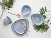 A set of blue ceramic dishes and a mug, arranged with greenery on a white background. Náhľad obrázku produktu