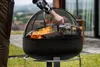 A person is tending to a fire pit outdoors, with a log burning inside. Produktbild-Vorschau