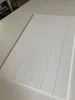 A white wall panel with vertical grooves, lying on a white surface. Produktbild-Vorschau
