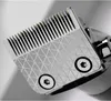A close-up view of the cutting head of a hair clipper, showing the metallic blades and a textured pattern on the casing. Produktbild-Vorschau