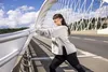 A woman is stretching on a bridge with a modern architectural design. Produktbild-Vorschau