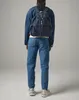 A person wearing a denim jacket and jeans, with a backpack on their back, stands against a plain background. Voir les images du produit