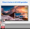 A television screen displaying a mountain landscape with resolution comparisons (UHD, FHD, HD) and marketing awards. The TV is placed on a shelf. Produktbild-Vorschau