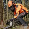 A person wearing safety gear and using a chainsaw in a forest. Produktbild-Vorschau