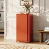 A red metal cabinet with two doors stands in a room with white paneled walls. A vase of pink tulips sits on top of the cabinet, and a stack of books and shoes are on a wooden bench to the right. Voir les images du produit