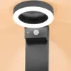 A close-up view of a modern, black outdoor solar light with a circular LED light and a motion sensor. Produktbild-Vorschau