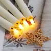 A close-up view of several LED candles with warm yellow light emanating from them, arranged on a surface with decorative elements like star anise and a woven star. Náhled obrázku produktu
