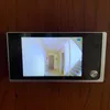 A digital peephole viewer mounted on a wooden door. Produktbild-Vorschau