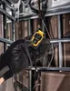A gloved hand holds a yellow and black DeWalt laser distance measurer in front of a wall with exposed studs and wiring. Anteprima dell’immagine prodotto