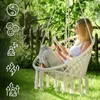 A woman is reading a book while sitting in a hanging chair in a garden. Podgląd zdjęcia produktu