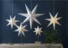 Several paper star lanterns of varying sizes are displayed against a dark blue wall. Produktbild-Vorschau