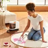 A woman is cleaning a rug with a carpet cleaner. Náhled obrázku produktu
