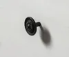 A close-up shot of a black, ornate drawer knob on a white wooden surface. Produktbild-Vorschau