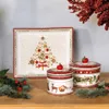 A festive Christmas-themed rectangular platter and two round lidded jars are arranged on a wooden surface, with pine branches and red berries as decoration. Anteprima dell’immagine prodotto