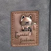 A close-up of a label on a bag featuring a metallic cat wearing glasses and the text "Town&fashion". Voir les images du produit