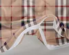 A close-up view of a beige plaid fabric with a white zipper closure. Náhľad obrázku produktu