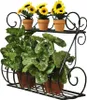 A black metal two-tiered plant stand holding artificial sunflowers on the top shelf and artificial ivy plants on the bottom shelf. Náhľad obrázku produktu
