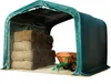 A green tarp shelter with hay bales and a farm implement inside. Voir les images du produit