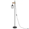 A black floor lamp with a wooden accent and a wire cage shade, shown against a white background. Produktbild-Vorschau