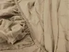 A close-up view of a beige fitted sheet, showing the elasticized edge and the texture of the fabric. Produktbild-Vorschau