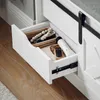 A close-up view of an open drawer in a white piece of furniture, revealing various items stored inside. Anteprima dell’immagine prodotto