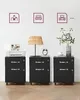 Three black filing cabinets are shown in a room with a white wall and wooden floor. Decorative icons are on the wall above the cabinets. Produktbild-Vorschau