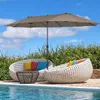 An outdoor patio scene with lounge chairs, a coffee table, and a large umbrella by a swimming pool. Náhľad obrázku produktu