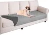 A dog is lying on a gray protective cover on a sofa. Náhled obrázku produktu