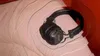 A pair of black Marshall headphones is placed on a pink surface, with concentric circles emanating from the headphones, suggesting sound waves. Voir les images du produit