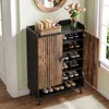 A shoe cabinet with its door open, displaying shoes on shelves, placed in a room with a mirror and flowers. Náhľad obrázku produktu